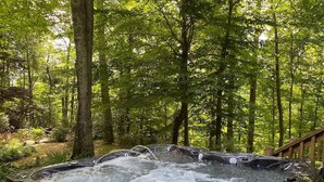 A hot tub in a forested area with a wooden deck.