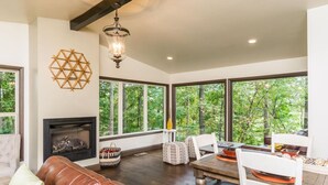 A spacious living room with a fireplace, large windows, and a dining area.
