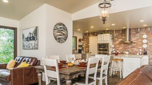 A dining area with a wooden table, white chairs, and a brown leather couch.