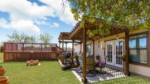 A backyard with a wooden pergola, a barbecue grill, and a patio table with chairs. - Spacious Home with Pool Sleeps 10  Near Lackland BMT Graduation Family Friendly (San Antonio)