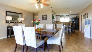 A spacious dining area with a large wooden table and matching chairs, a ceiling fan, and a kitchen in the background. - Spacious Home with Pool Sleeps 10  Near Lackland BMT Graduation Family Friendly (San Antonio)