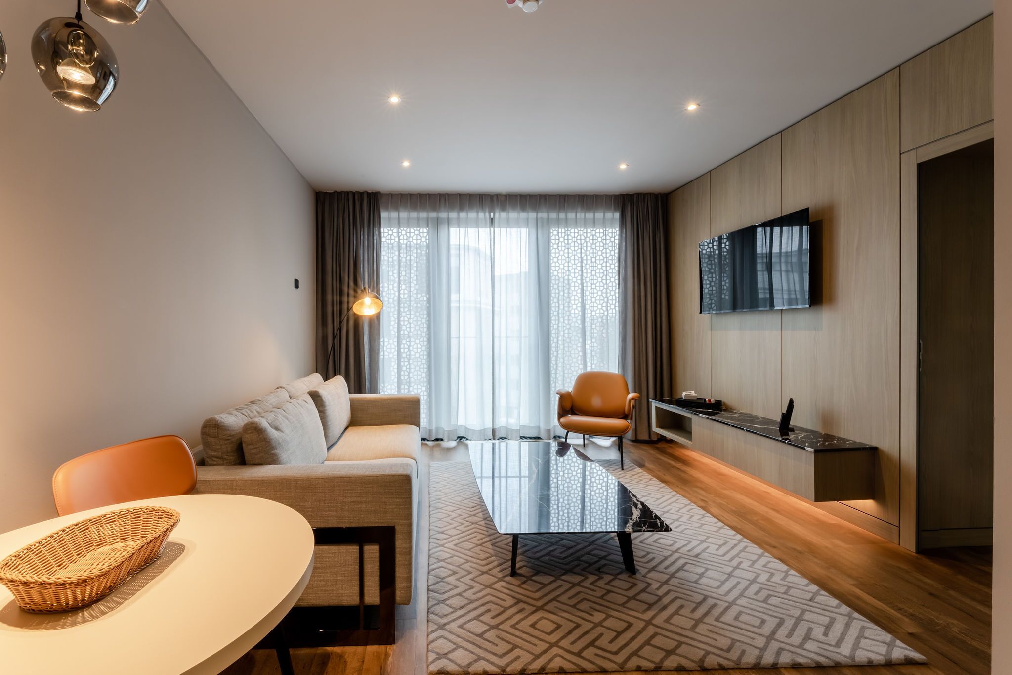 A modern living room with a sofa, a coffee table, and a TV mounted on the wall.
