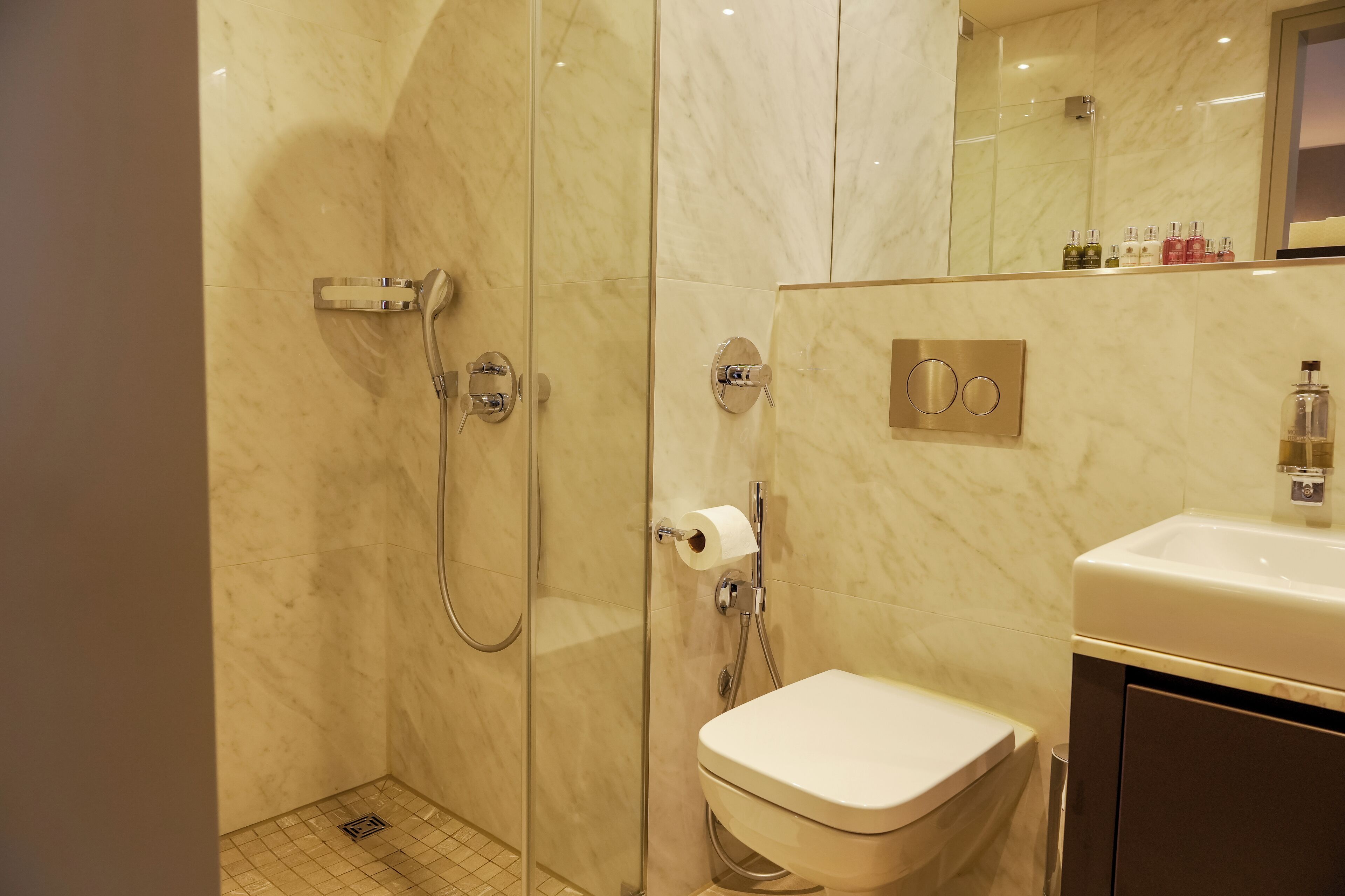 A modern bathroom with a glass-enclosed shower, a toilet, and a sink.