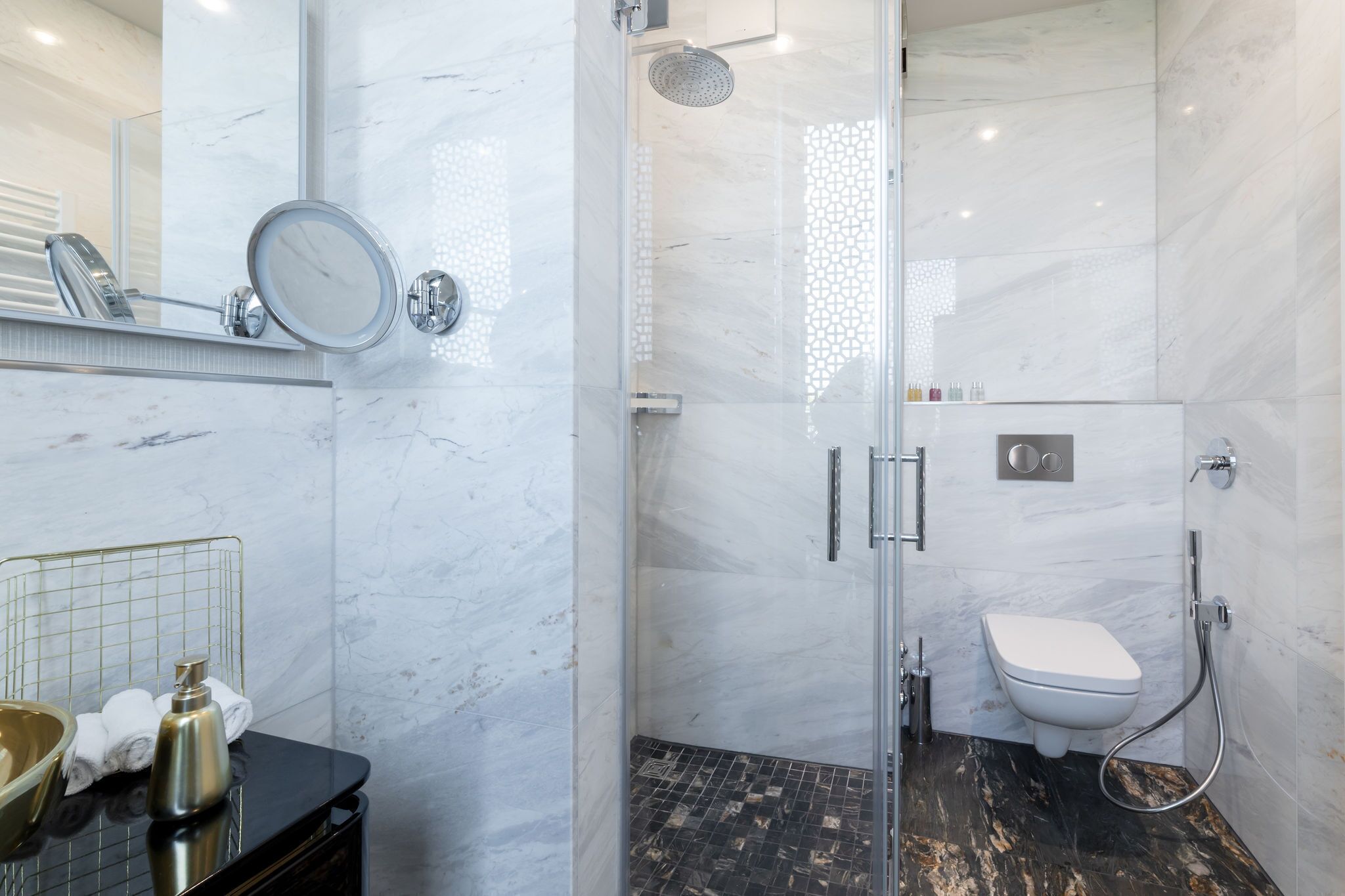 Un baño moderno con cabina de ducha de vidrio, un inodoro y un lavamanos con espejo.