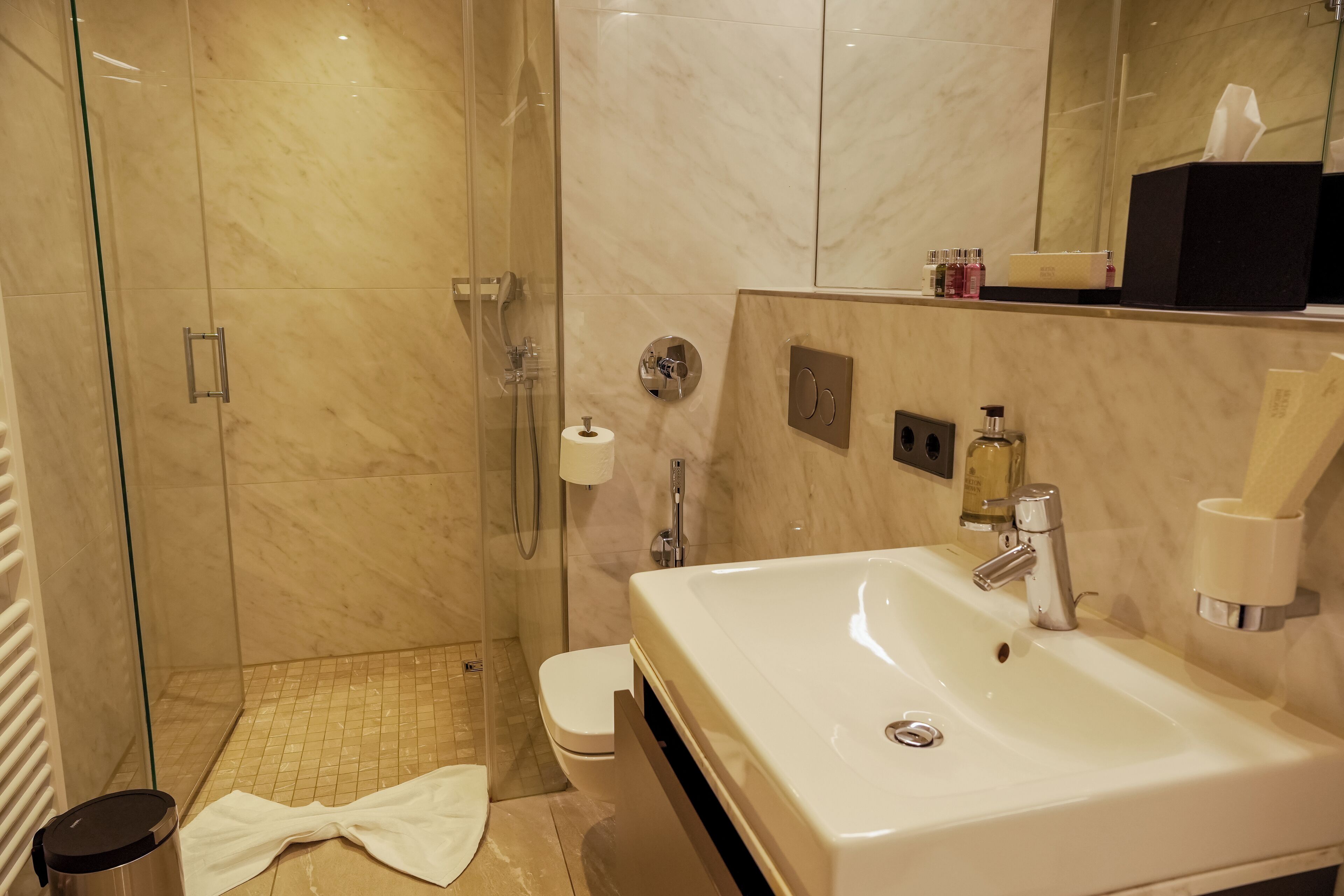 A modern bathroom with a glass-enclosed shower, a white sink, and a toilet.