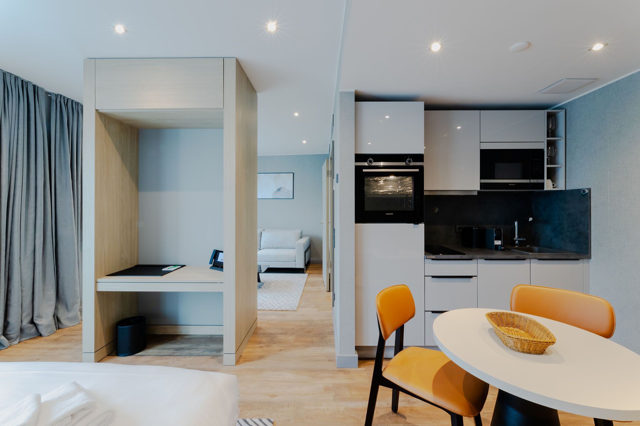 Una habitación de hotel moderna con kitchenette, comedor y zona de descanso separada.