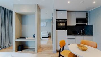 Una habitación de hotel moderna con kitchenette, comedor y zona de descanso separada.