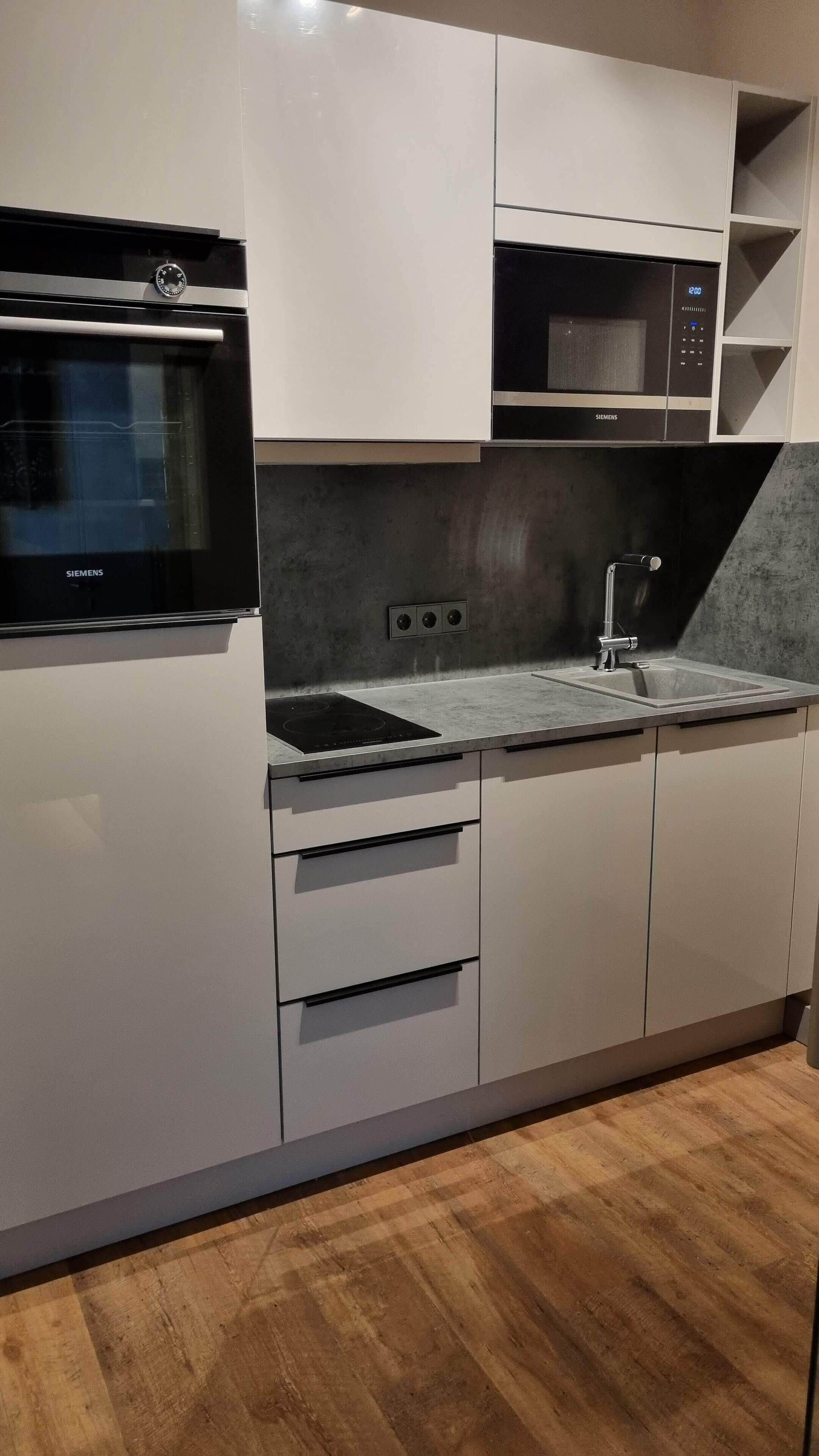Eine moderne Küche mit integriertem Mikrowellenherd, Backofen und Spüle.