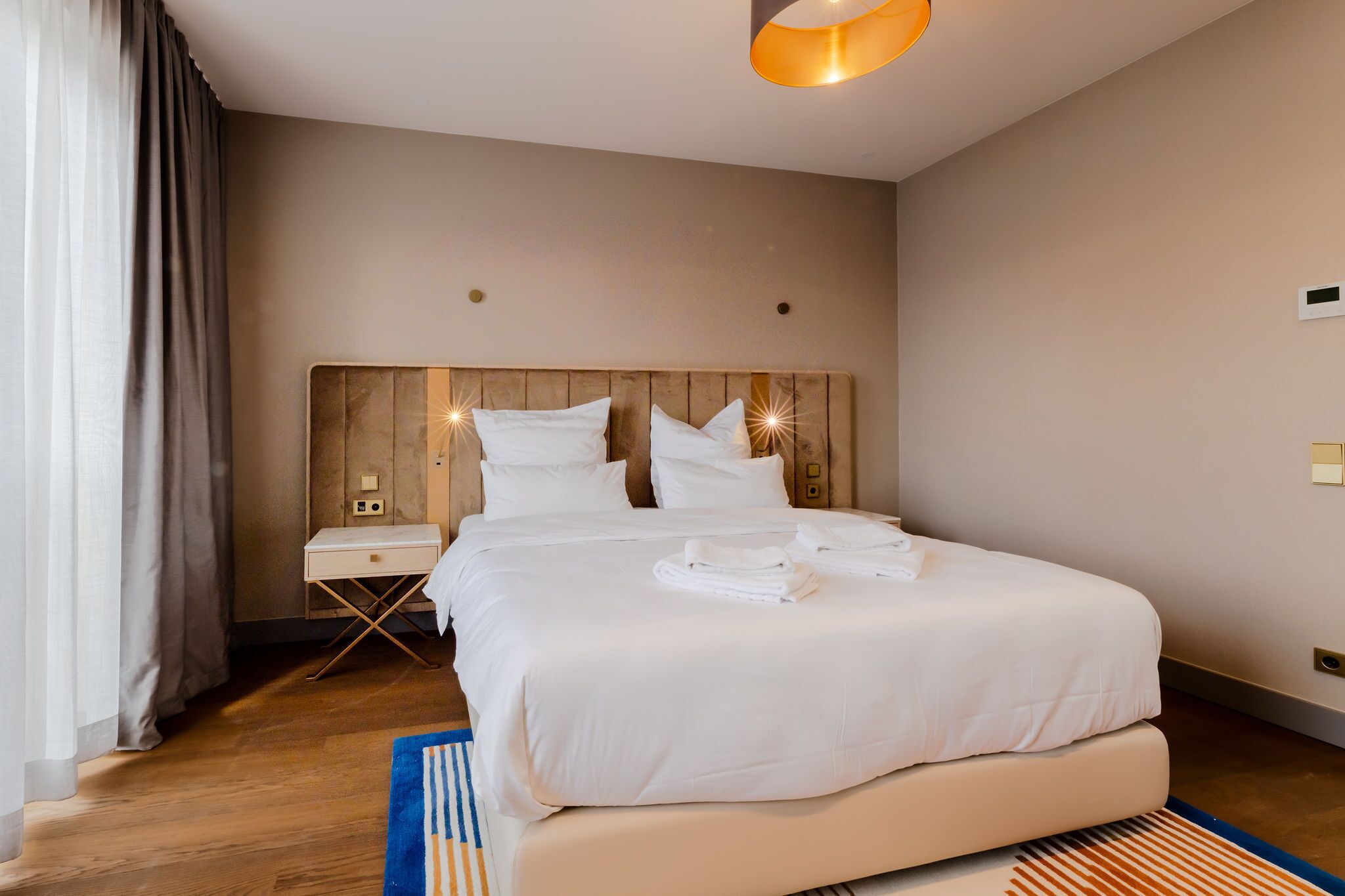 A hotel room with a large bed, a bedside table, and a lamp.