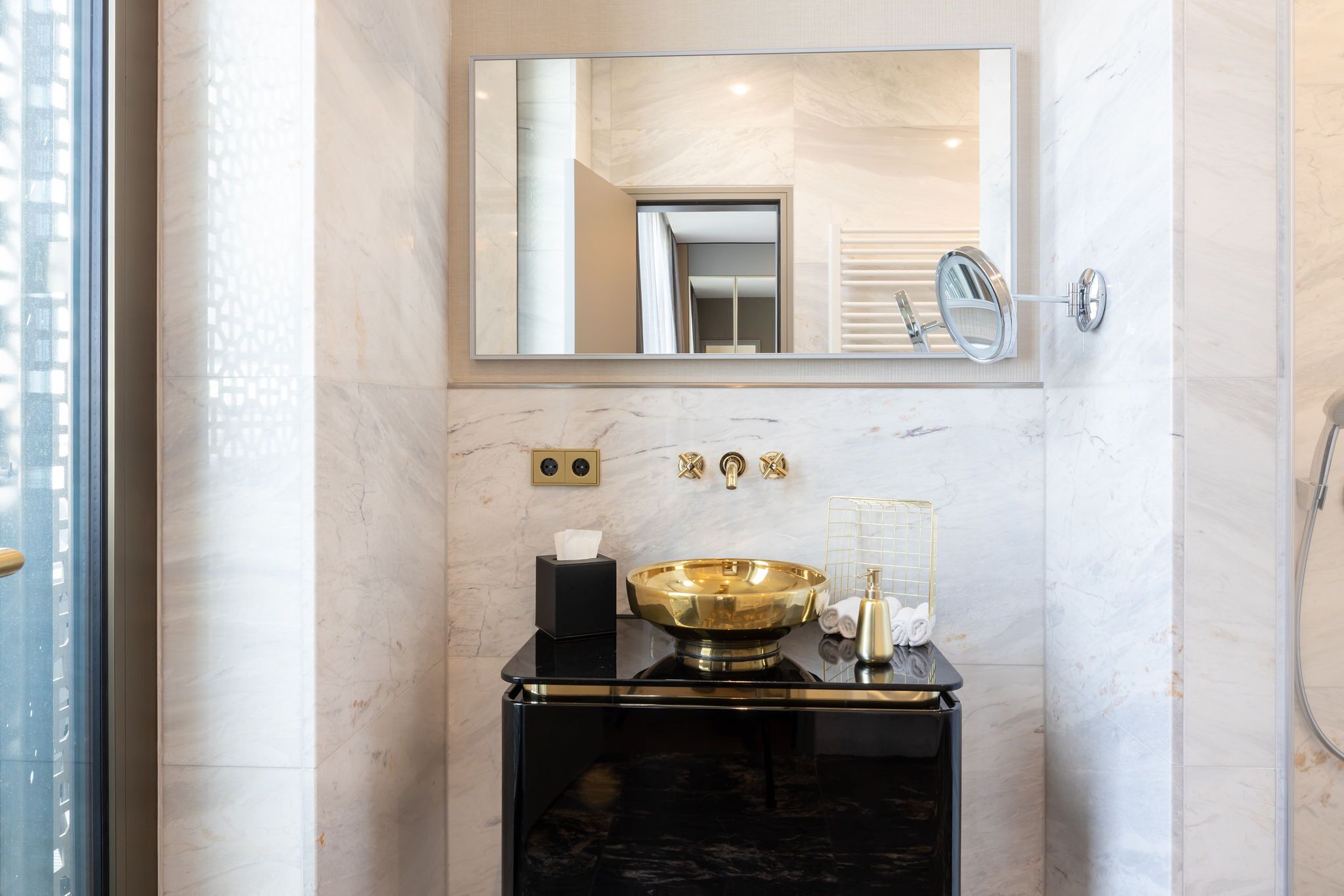 A bathroom with a black vanity, a gold basin, a mirror, and a towel rack.