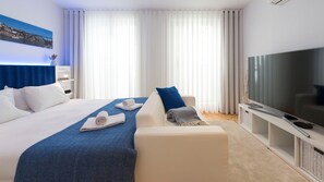 Une chambre d’hôtel moderne avec un grand lit, un canapé, une télévision et une vue sur la ville.