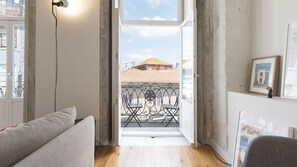 Ein offener Balkon mit schmiedeeisernem Geländer, Blick auf Gebäude und ein gerahmtes Bild an der Wand.