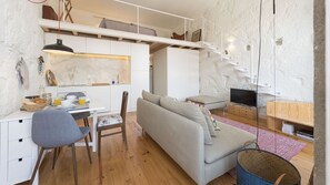 A compact living space with a kitchenette, a sofa, a dining area, and a TV. - Cativo Mezzanine Studio by LovelyStay (Porto)