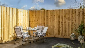 Eine Holzterrasse mit Tisch und Stühlen, umgeben von einem Holzzaun.