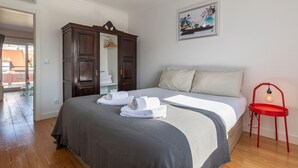 Een slaapkamer met een bed, een garderobe, een rode stoel en een schilderij aan de muur.