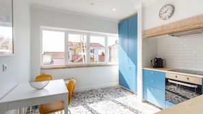 A modern kitchen with a window, blue cabinets, a coffee machine, and a patterned floor.