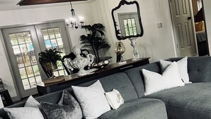 A grey sectional sofa with white and patterned cushions, a white rug, and a wooden coffee table with decorative items.