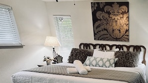 A neatly made bed with a white and gray duvet, a wooden headboard, and multiple pillows.
