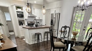 A modern kitchen with white cabinets, stainless steel appliances, and a central island with bar stools.