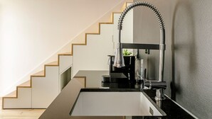 Eine moderne Küche mit einer glatten schwarzen Arbeitsplatte, einem Edelstahl-Spülbecken und einem Bogen-Wasserhahn.