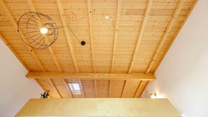 A room with a wooden ceiling, a skylight, and a hanging light fixture.