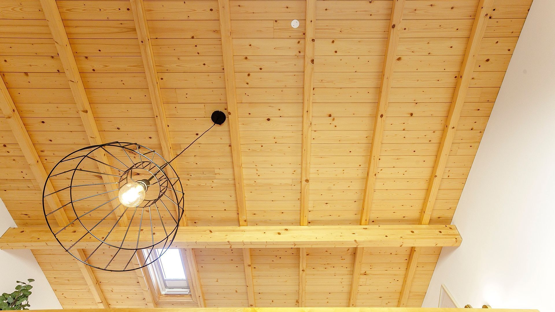Eine hohe Decke mit Holzbalken und einer einzelnen Lampe.