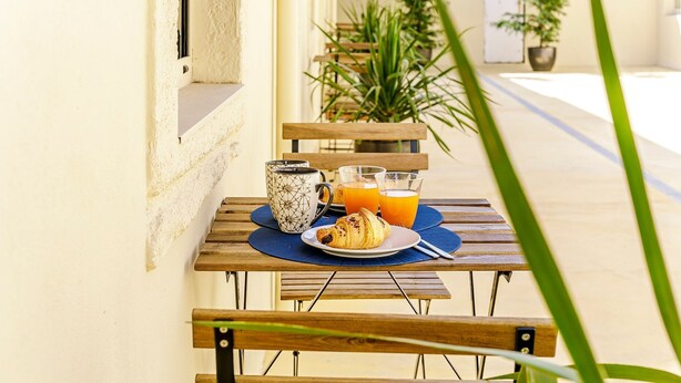Uma mesa de madeira com um prato de comida, uma caneca e copos de suco de laranja.