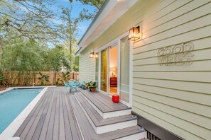 A house with a pool, a deck, and a sign that reads 'GOOD VIBES'.