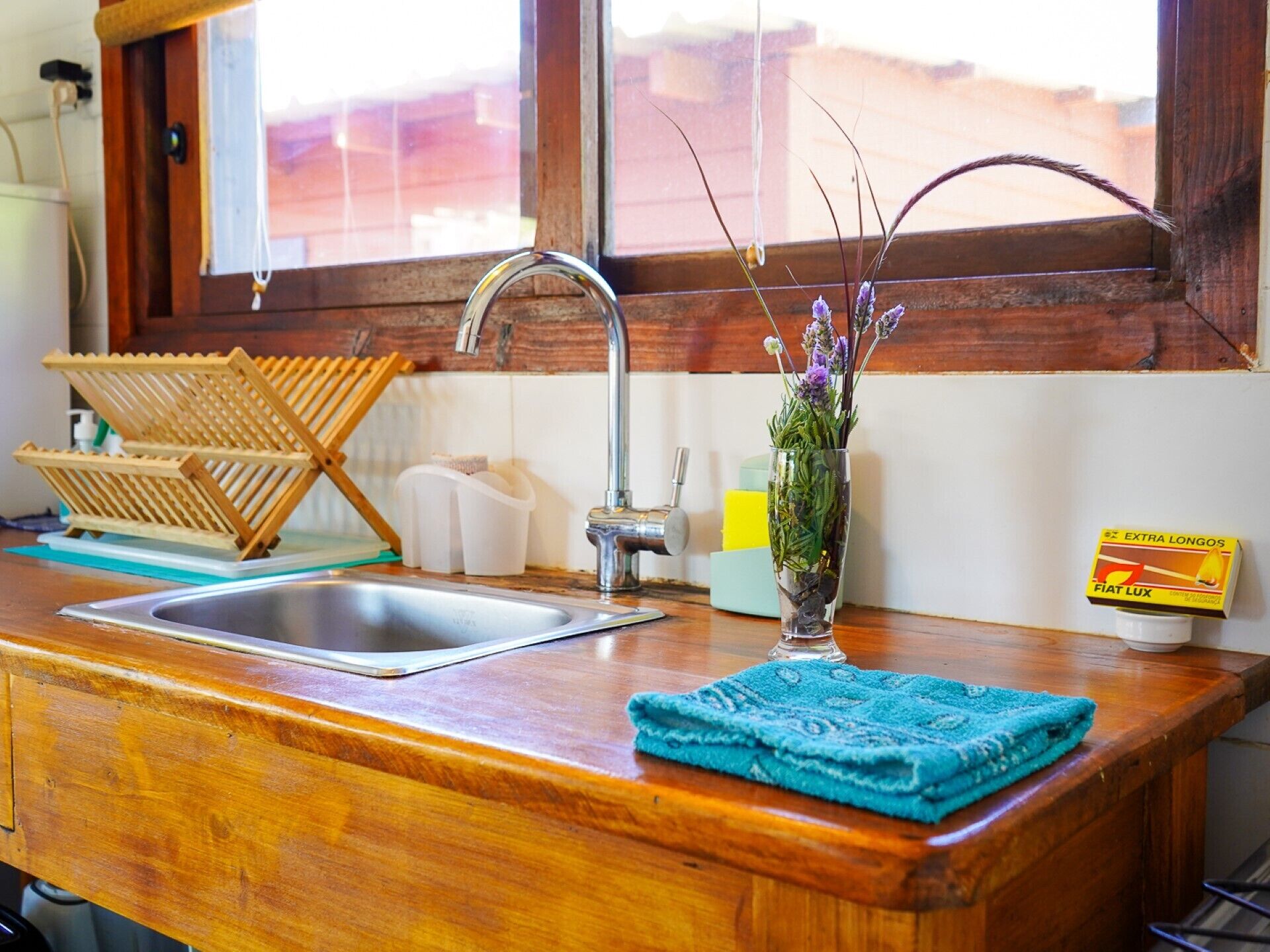 A kitchen with a wooden countertop, a sink, a window, and a vase with flowers.