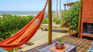 A wooden deck with a hammock, lounge chairs, and a small table with a potted plant. - Cabañas Kundalini Punta de Diablo (Punta del Diablo)