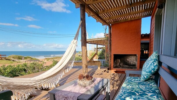 A wooden deck with a hammock, a fire pit, and a view of the ocean. - Cabañas Kundalini Punta de Diablo (Punta del Diablo)