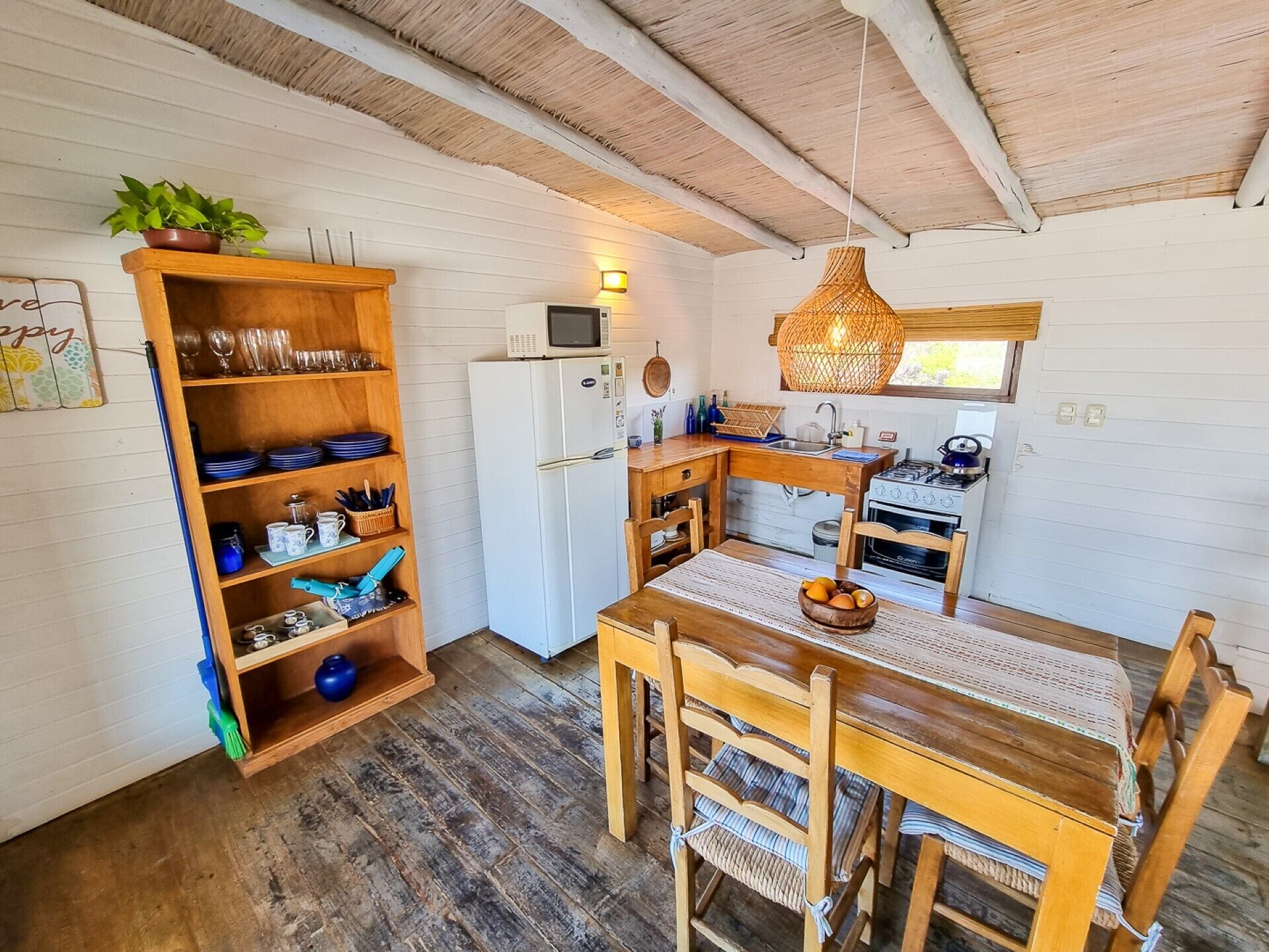 A compact kitchen with a wooden table, chairs, a microwave, and a stove.
