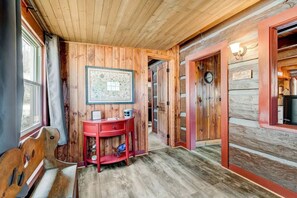 A wooden interior with a desk, a framed picture, and a red chair.