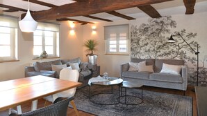 Ein gemütliches Wohnzimmer mit Holzboden, zwei grauen Sofas, einem Holztisch und einem großen Teppich.