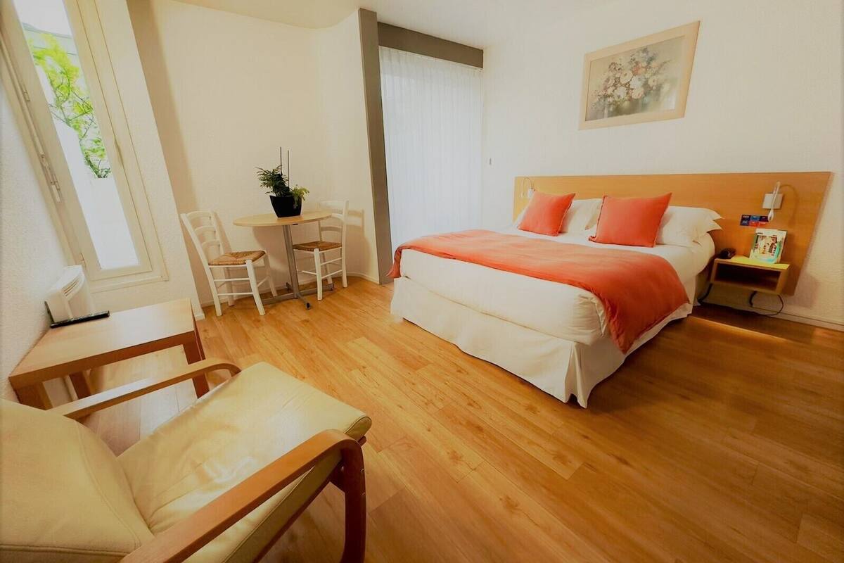 Een slaapkamer met een bed, nachtkastje en een raam met gordijnen.