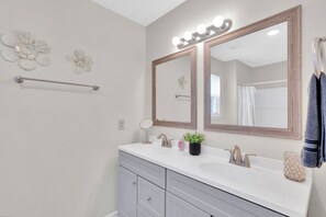 Un bagno con due lavabi, un mobile vanità, uno specchio grande illuminato e decorazioni murali.