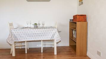 A dining area with a table set for four, a bookshelf, and a sign on the wall.