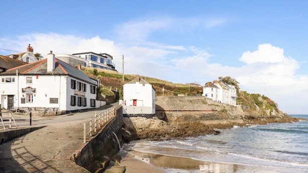 Un edificio costiero con una scala in pietra che conduce alla spiaggia, un cartello con la scritta 'The King's Inn' e vista sul mare.