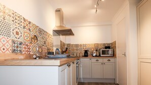 Una cucina compatta con zoccolo paraschizzi decorato, forno a microonde, tostapane e piano di lavoro in legno.