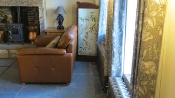 A cozy living room with a stone fireplace, a leather sofa, and patterned curtains.