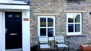 A stone building with a black door, a sign reading "Farthing Cottage," and two white windows with green frames. - Farthing Cottage (Bishop Auckland)