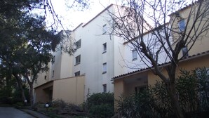 A multi-story residential building with a flat facade, multiple windows, and a yellow curb. - Apartment (Saint-Mandrier-sur-Mer)