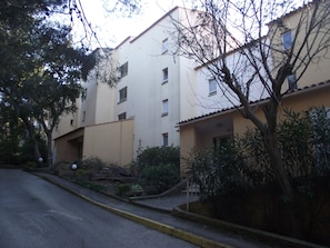 Un edificio residencial de varios pisos con fachada plana, varias ventanas y una acera amarilla.