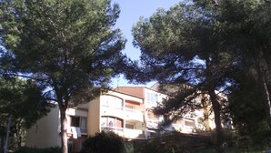 A multi-story residential building with balconies, surrounded by trees and greenery. - Apartment (Saint-Mandrier-sur-Mer)