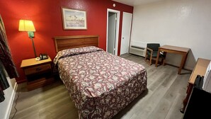 A hotel room with a bed, bedside table, lamp, desk, chair, and a radiator. - Western Motel (Abilene)