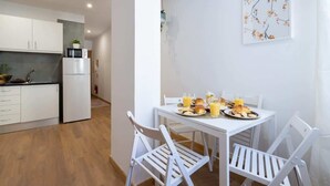 A modern kitchen with white cabinets, a refrigerator, and a dining area with a white table and chairs. - Peaceful & Sunny Building |One Terrace by HostWise (Porto)
