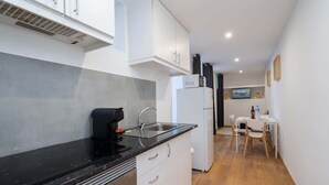 A compact kitchen with white cabinets, a black countertop, and a small dining area with a table and chairs. - Peaceful & Sunny Building |One Terrace by HostWise (Porto)
