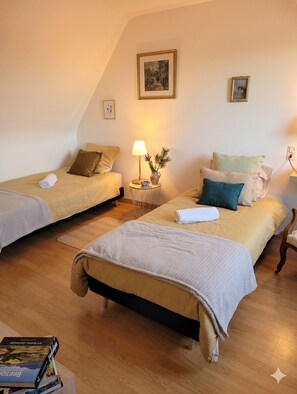 Una habitación acogedora con dos camas, una mesita con una lámpara y un cuadro en la pared.