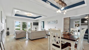 A spacious living room with a dining area, large windows, and a 'SUN AND FUN' sign. - THE ULTIMATE LAKEHOUSE (Lake Geneva)