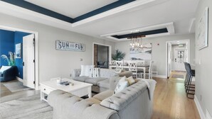 A modern living room with a sectional sofa, a coffee table, and a dining area with a chandelier. - THE ULTIMATE LAKEHOUSE (Lake Geneva)